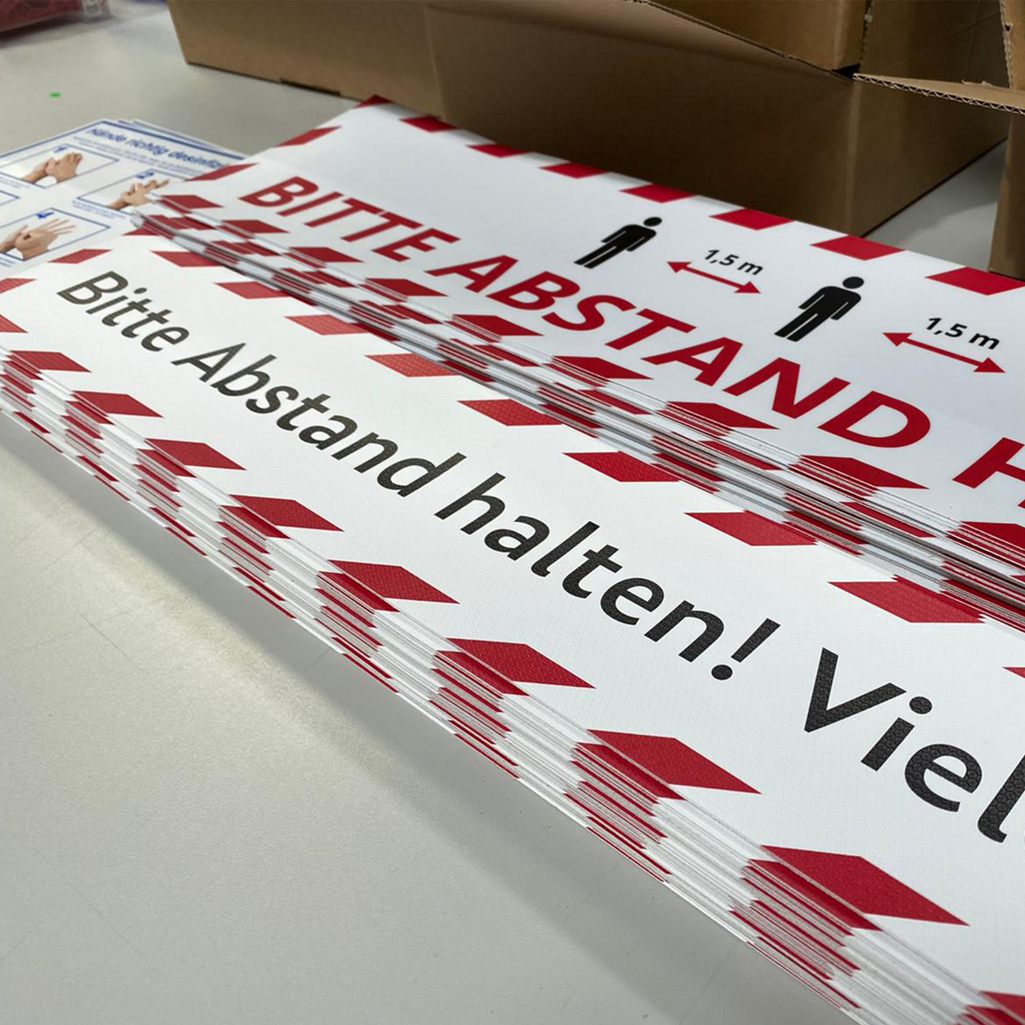 Fußbodenaufkleber 700x100 mm mit "Bitte Abstand halten! Vielen Dank!" von aufkleberdrucker.de auf glatter Bodenfläche.
